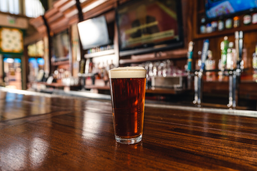 Pint of cold beer atop a wood bar at the Pint & Platter Irish Pub