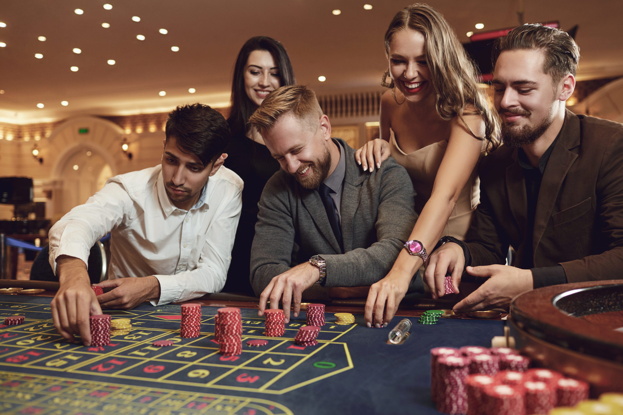 Happy friends play roulette in a casino as a 21st birthday idea.