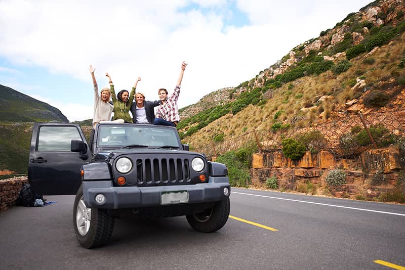 Friends waving their hands in the air out of the top of a Jeep celebrating Oktoberfest at the Jeep Raffle in Ouray Colorado