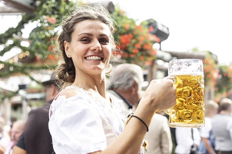 A woman smiling while holding a beer during Oktoberfest