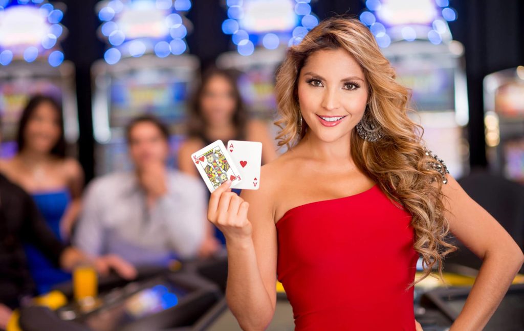 Women in a red dress holding an Ace & King in front of a Blackjack table.