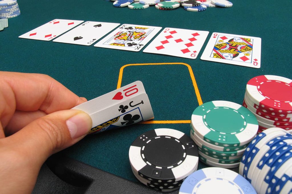 A hand holding the hole cards on a texas hold'em table