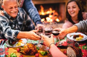 Family sitting around a thanksgiving table while toasting wine glasses.