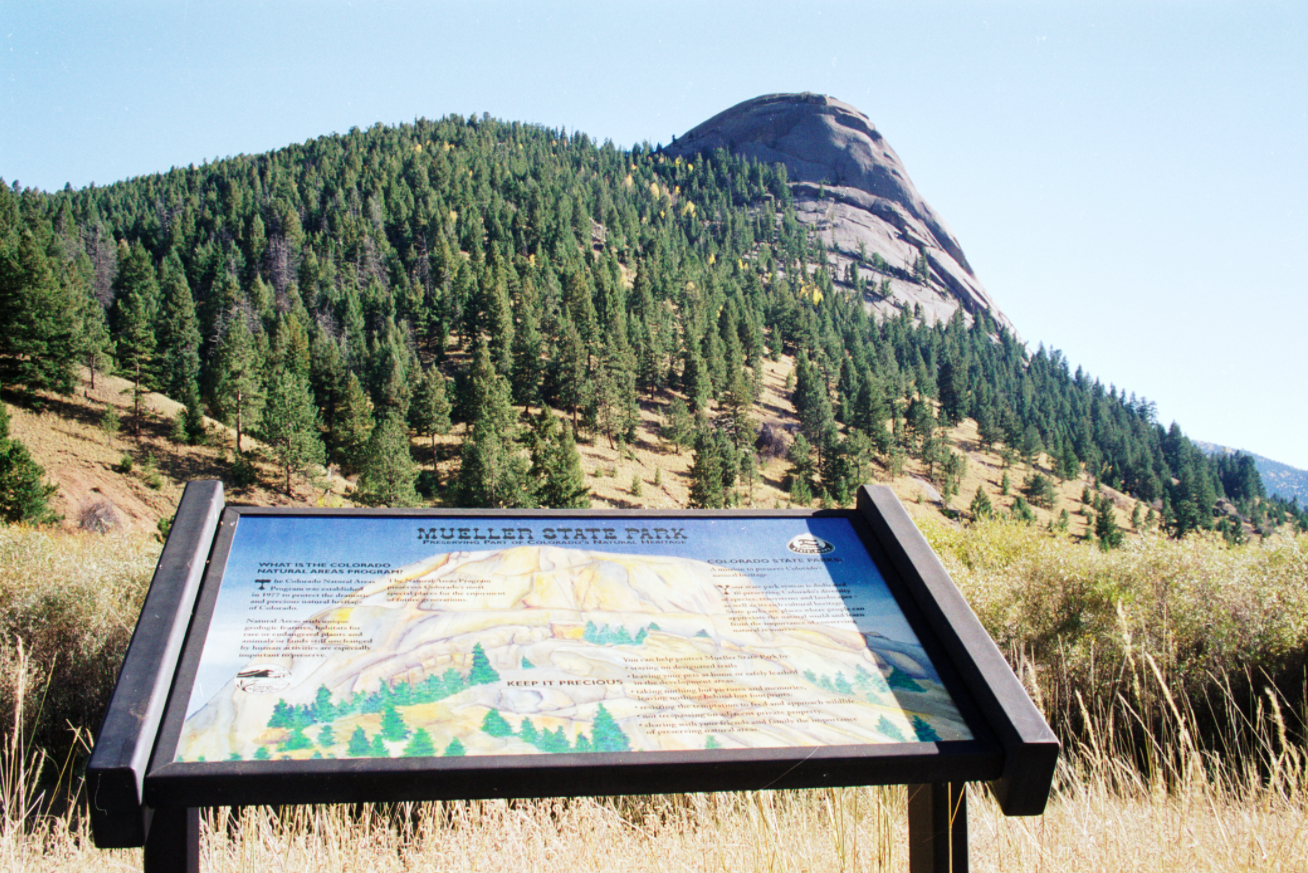 A view of a map of the Mueller State Park on a sunny day with a pine covered mountain in the distance