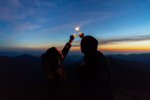 The man and a woman hold firework sticks. evening night time