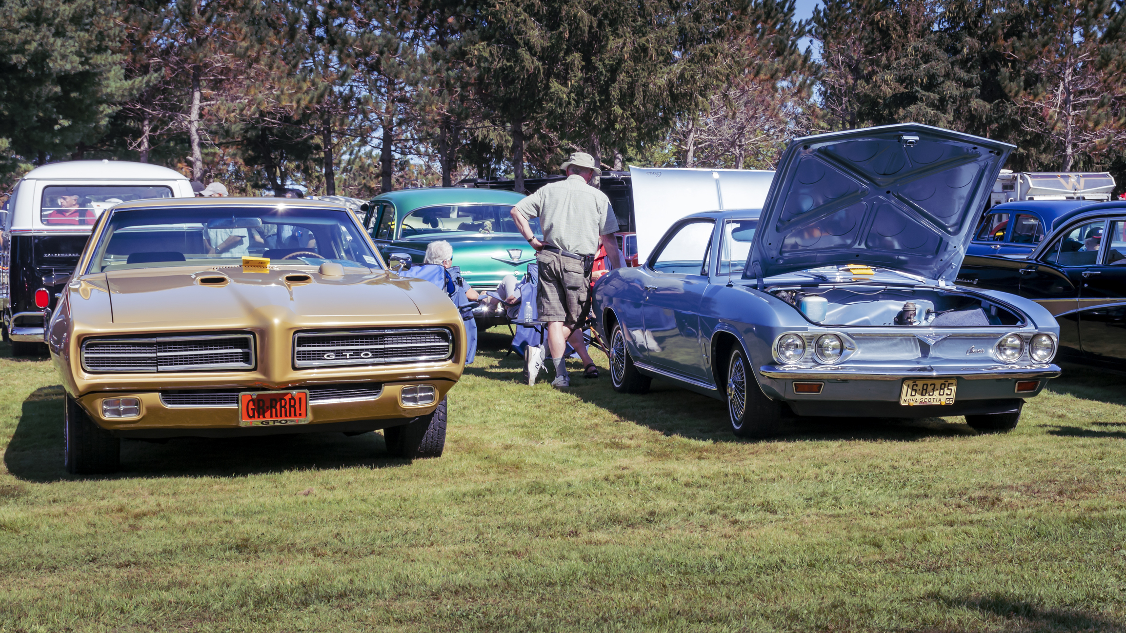 Hilden, Nova Scotia, Canada - September 21, 2019 : A pair of classic General Motors cars, 1969 Pontiac GTO & 1966 Chevrolet Corvair at Scotia Pine Show & Shine at Scotia Pine Campground. A man stands near the rear of the Corvair with hand on rear fender.
