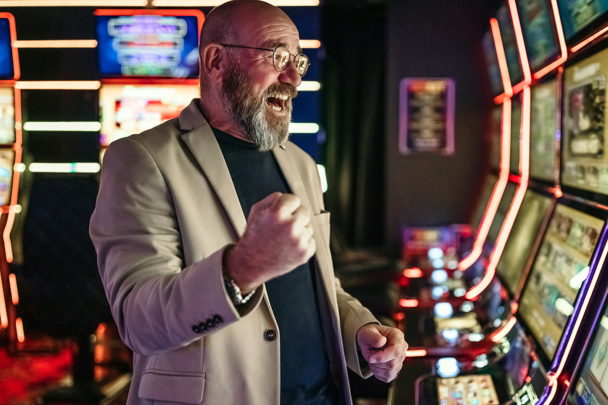 Senior men using slot machine to gamble in night club, having a good luck