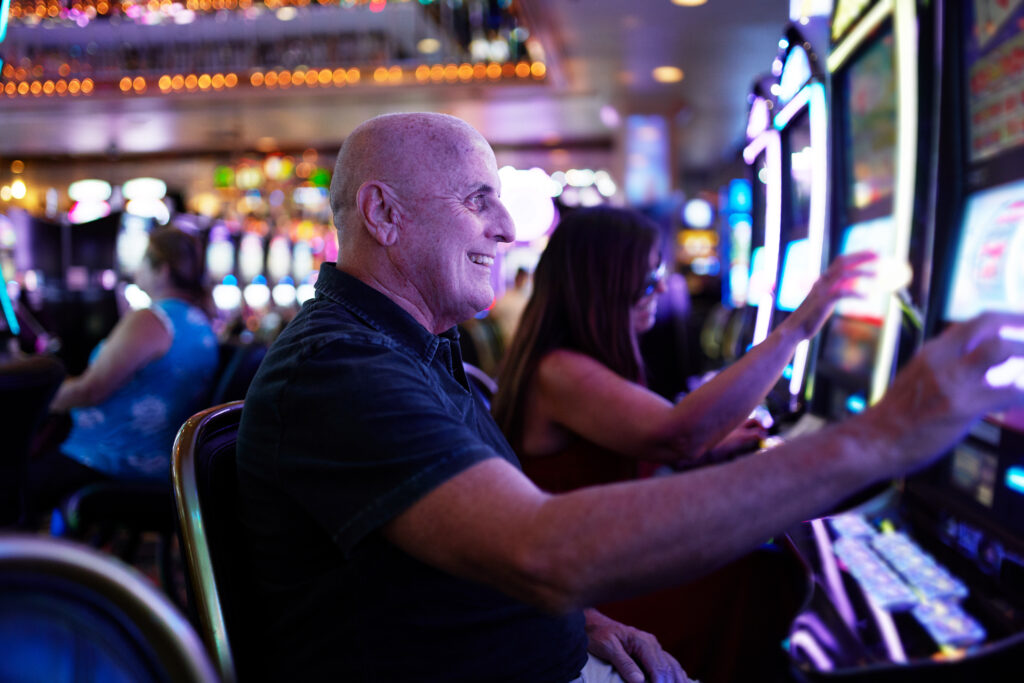 elderly tourist playing slot machines and gambling in casino