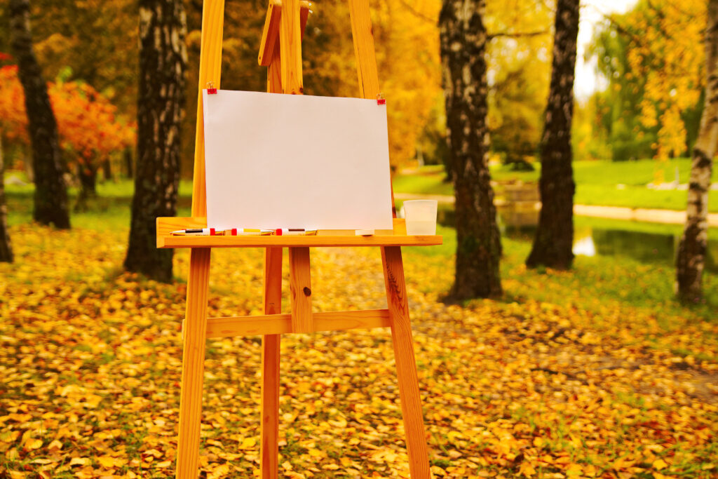 autumn landscape in the park stands the artist's easel with an empty sheet of paper for drawing.