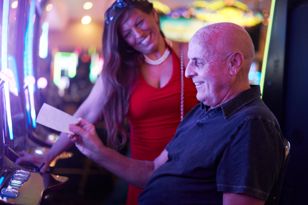 happy mature couple with payout ticket at casino