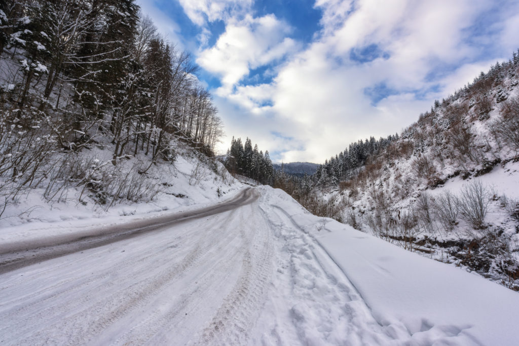 Narrow winding mountain road in snow, daytime winter landscape w