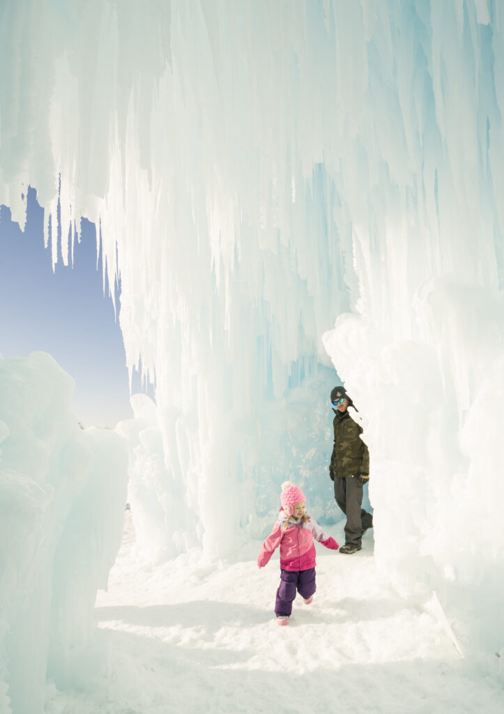 A parent following their child as they explore the magic of the ice castles.