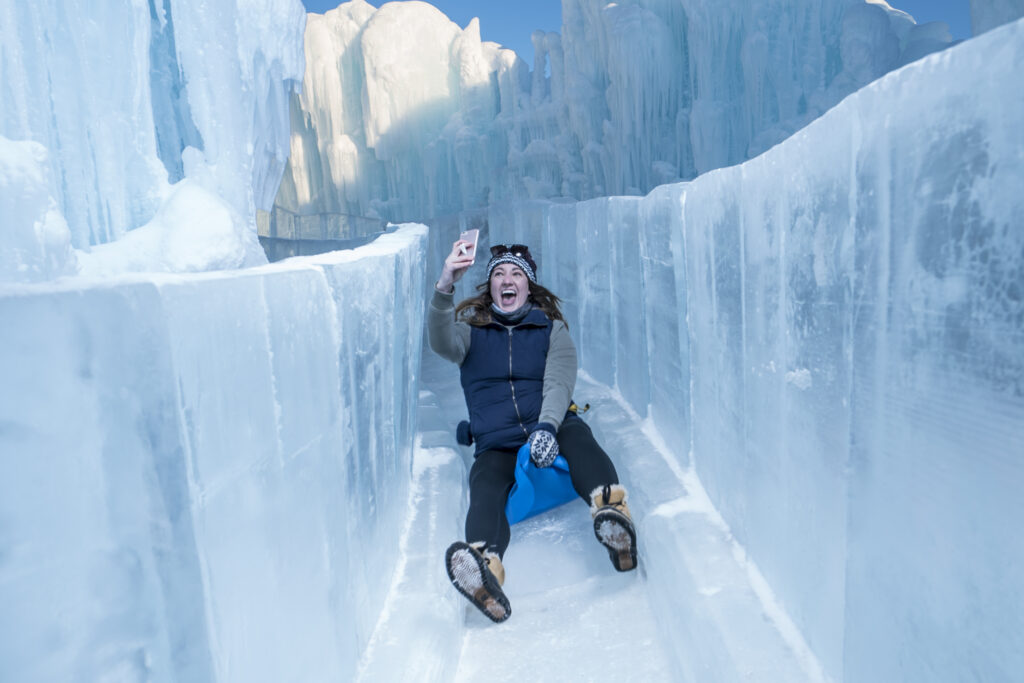 A woman sliding down an ice slide at the Ice Castles.