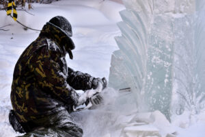 Worker using a chainsaw carving an ice sculpture