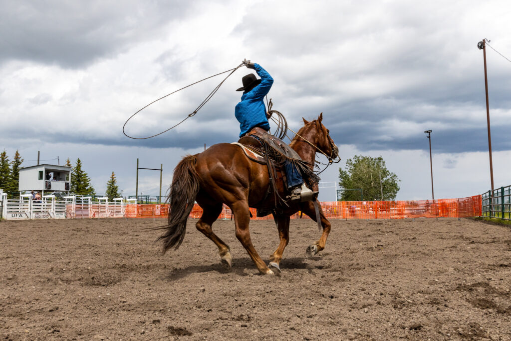 A man throwing a lasso off a horse.